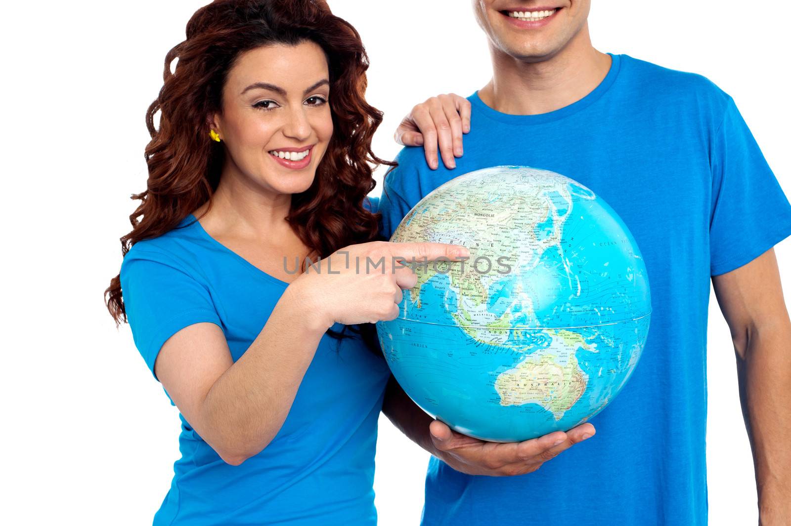 Woman pointing at China on globe while man holds it. Cropped image, man smiling