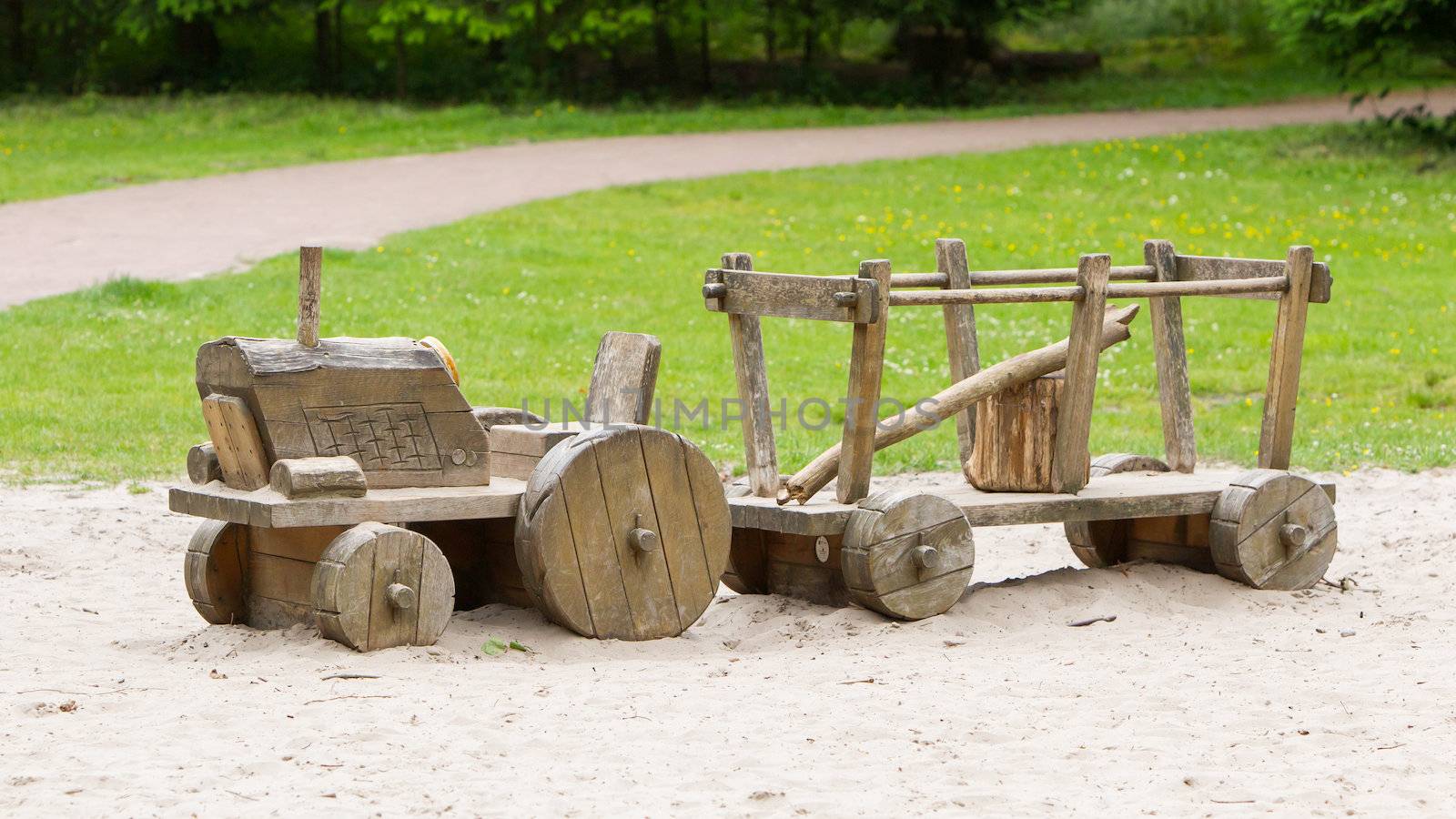 Wooden toy tractor with trailer in the sand