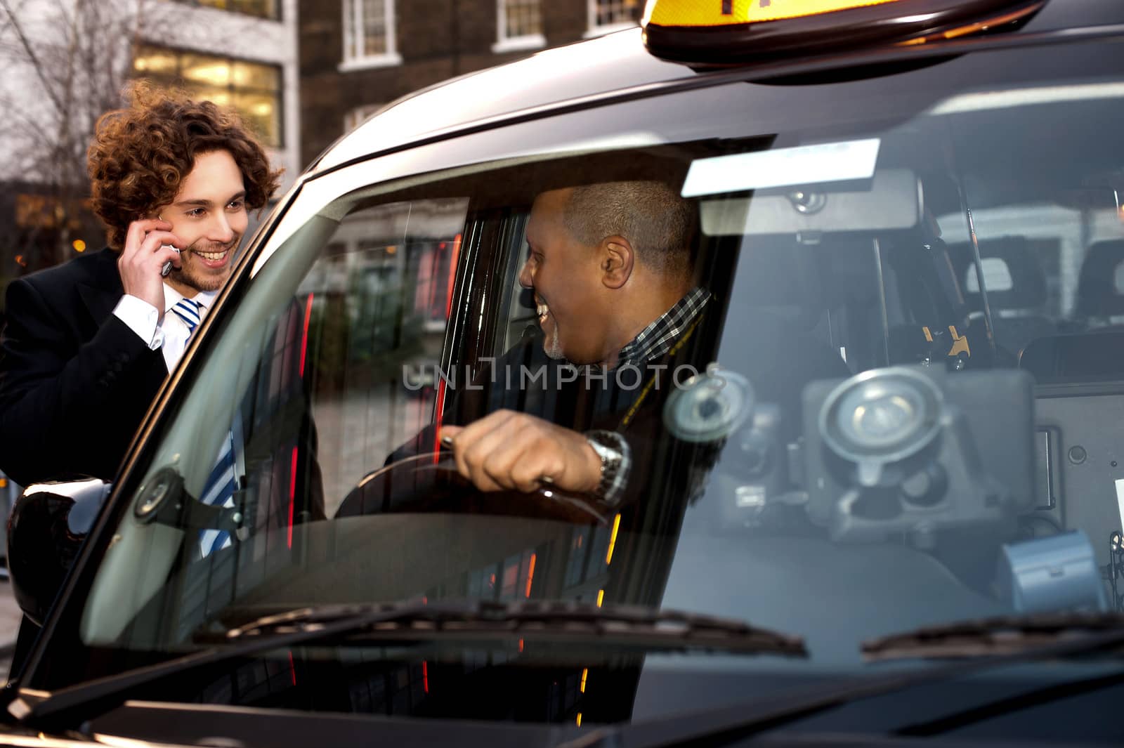 Taxi cab driver communicating with male passenger.