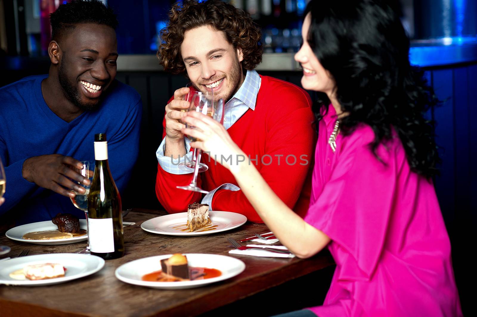 Friends enjoying dinner at restaurant by stockyimages