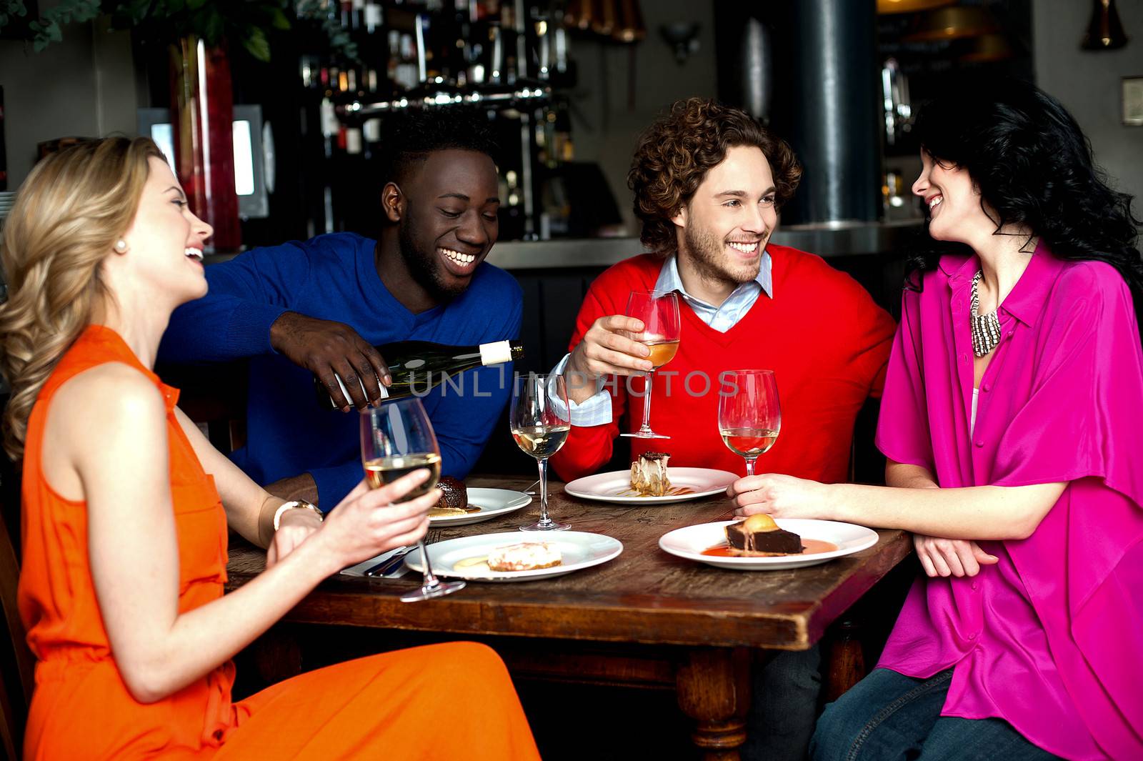 Four friends enjoying dinner at a restaurant by stockyimages