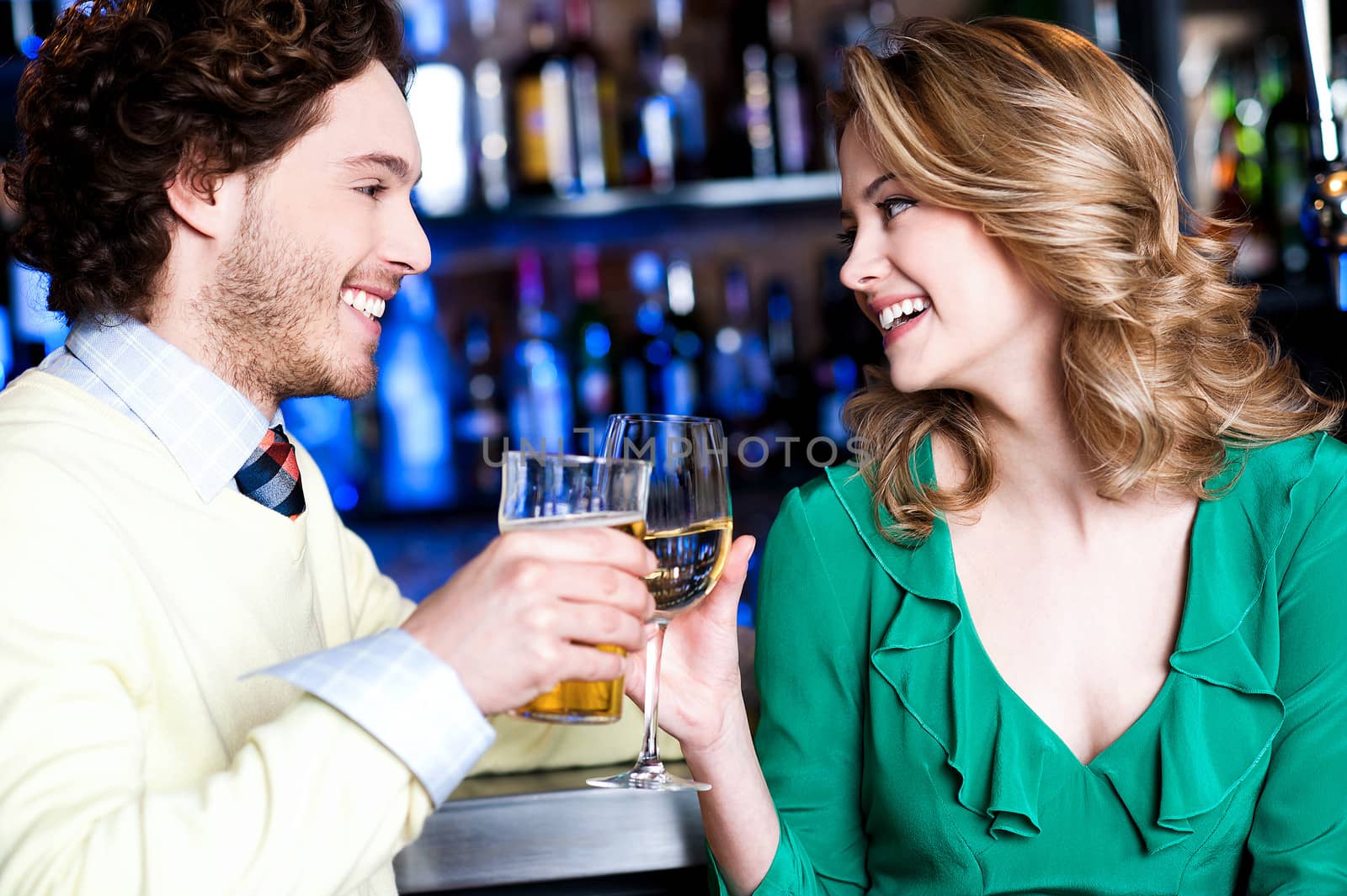 Cheerful two friends celebrating their drink in a bar