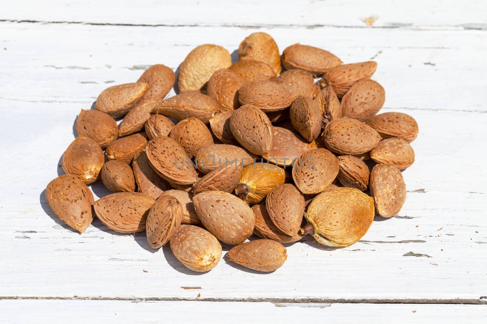 Almonds unpeeled nuts on white wooden background, closeup