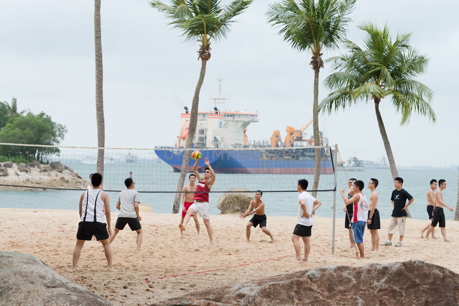 SENTOSA, SINGAPORE - SEP 10: Group of men play volleyball on beach at Sep 10, 2012 on Sentosa, Singapore. Sentosa is a popular island resort, visited by more than five million people a year.