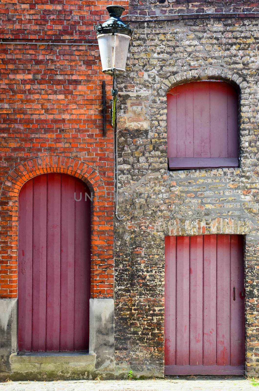 Detail of old vintage brick wall with red wooden doors and windows