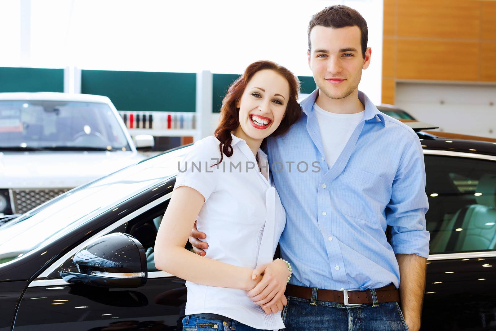 Two pretty young people smiling standing near car