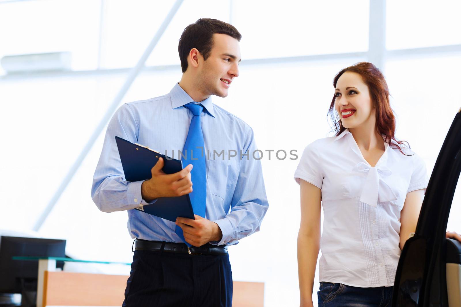 Attractive woman at car salon with consultant choosing a car