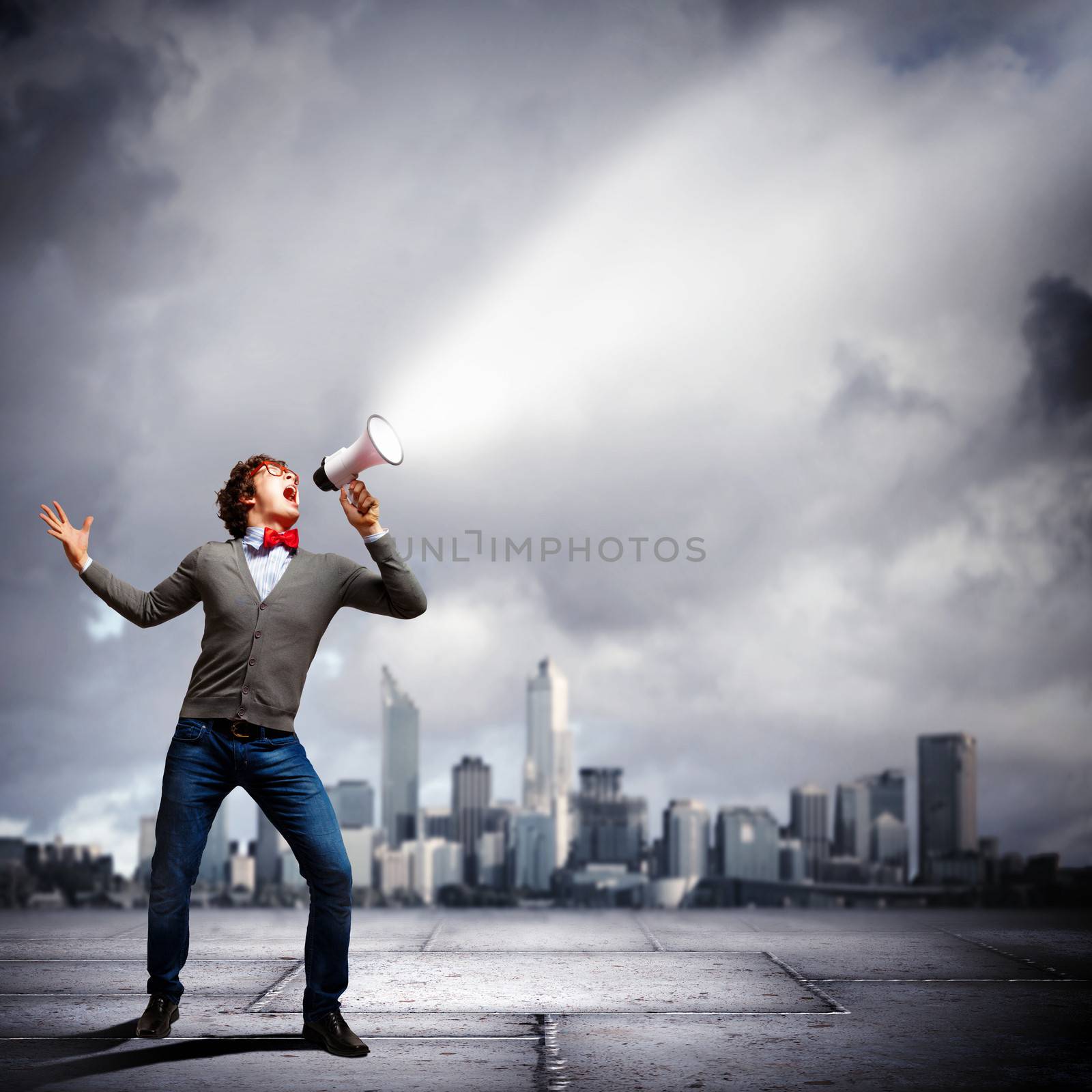 Portrait of young man shouting loudly using megaphone