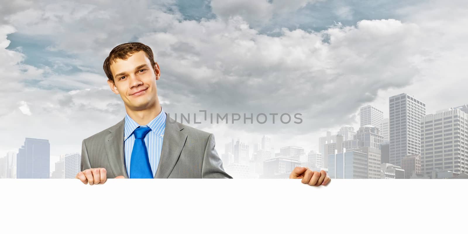 Businessman with blank banner standing against urban scenic. Place for text