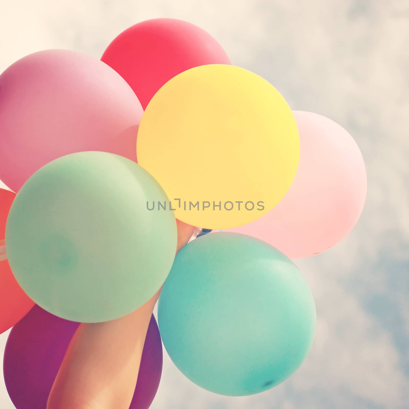 Hand holding multicolored balloons with retro filter effect