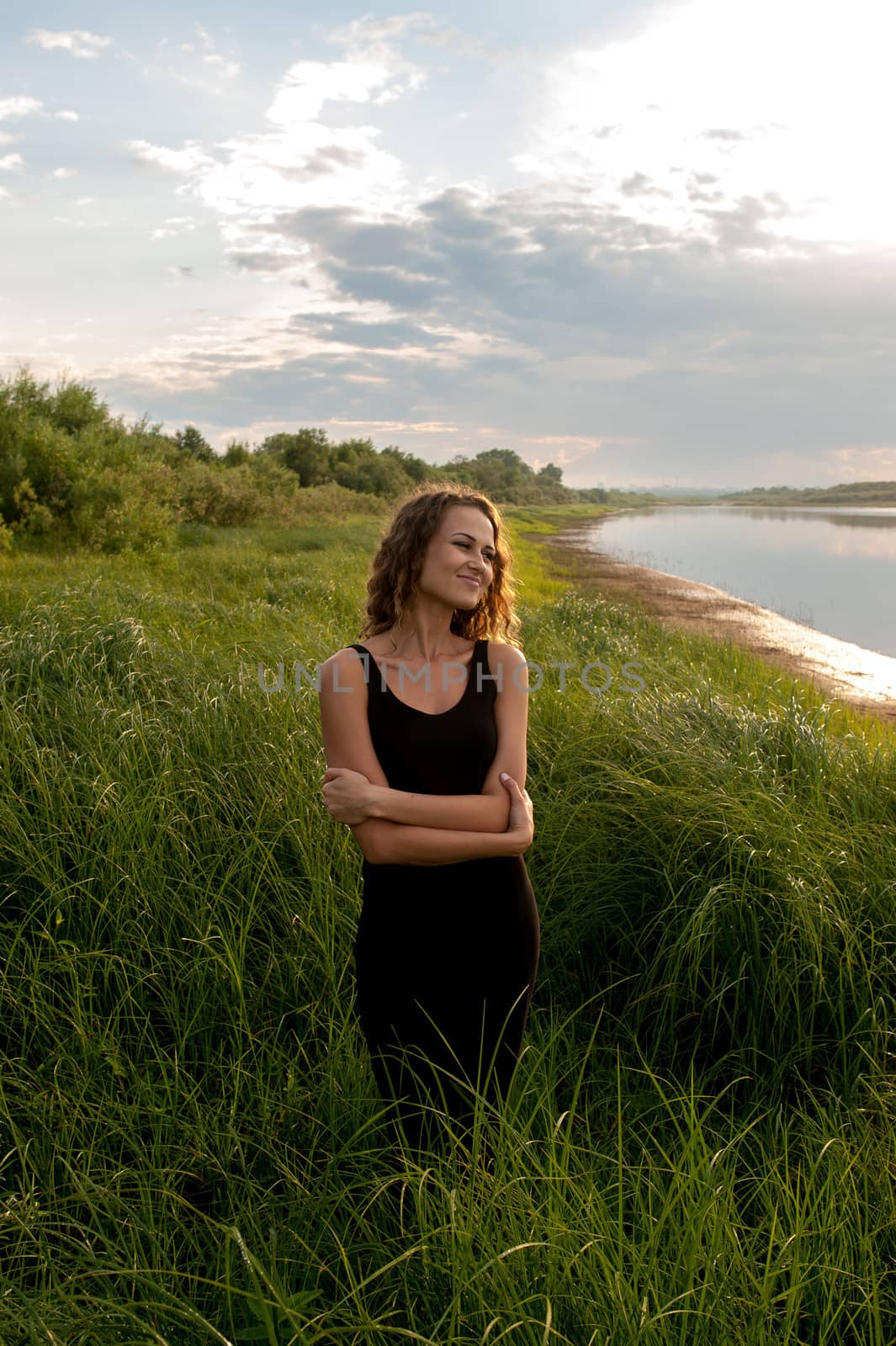 Beautiful girl walks and dreams in high grass on the banks of river