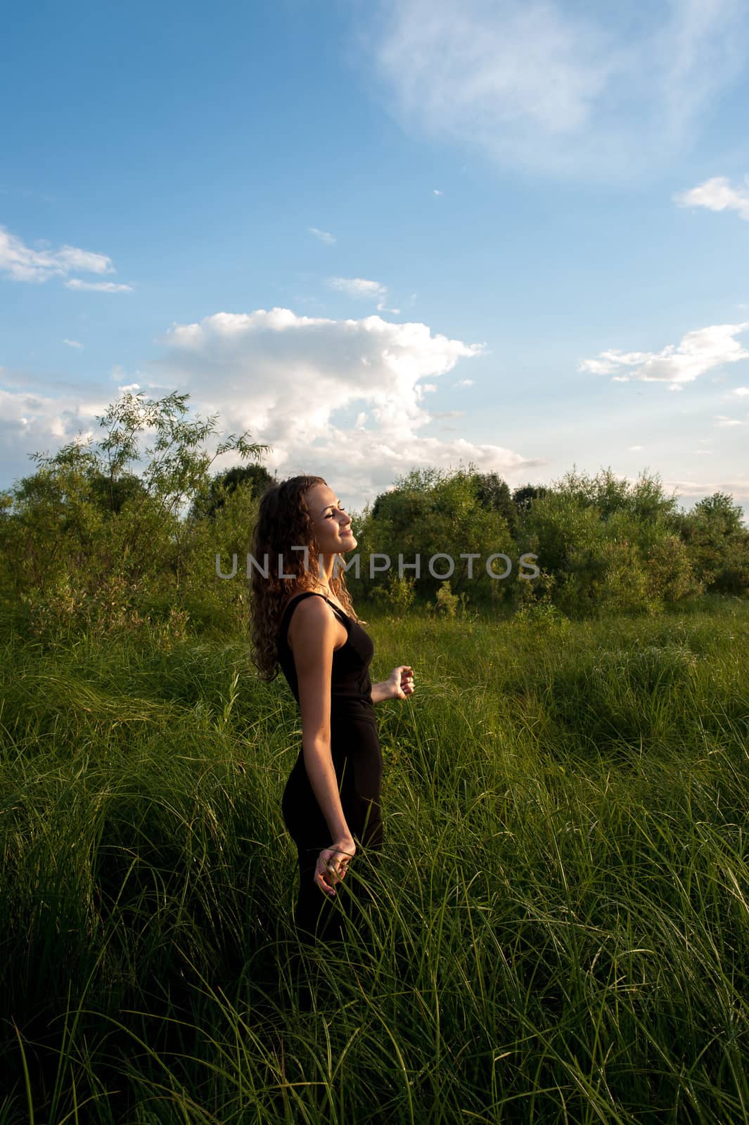 Beautiful girl walks and dreams in high grass on the banks of river