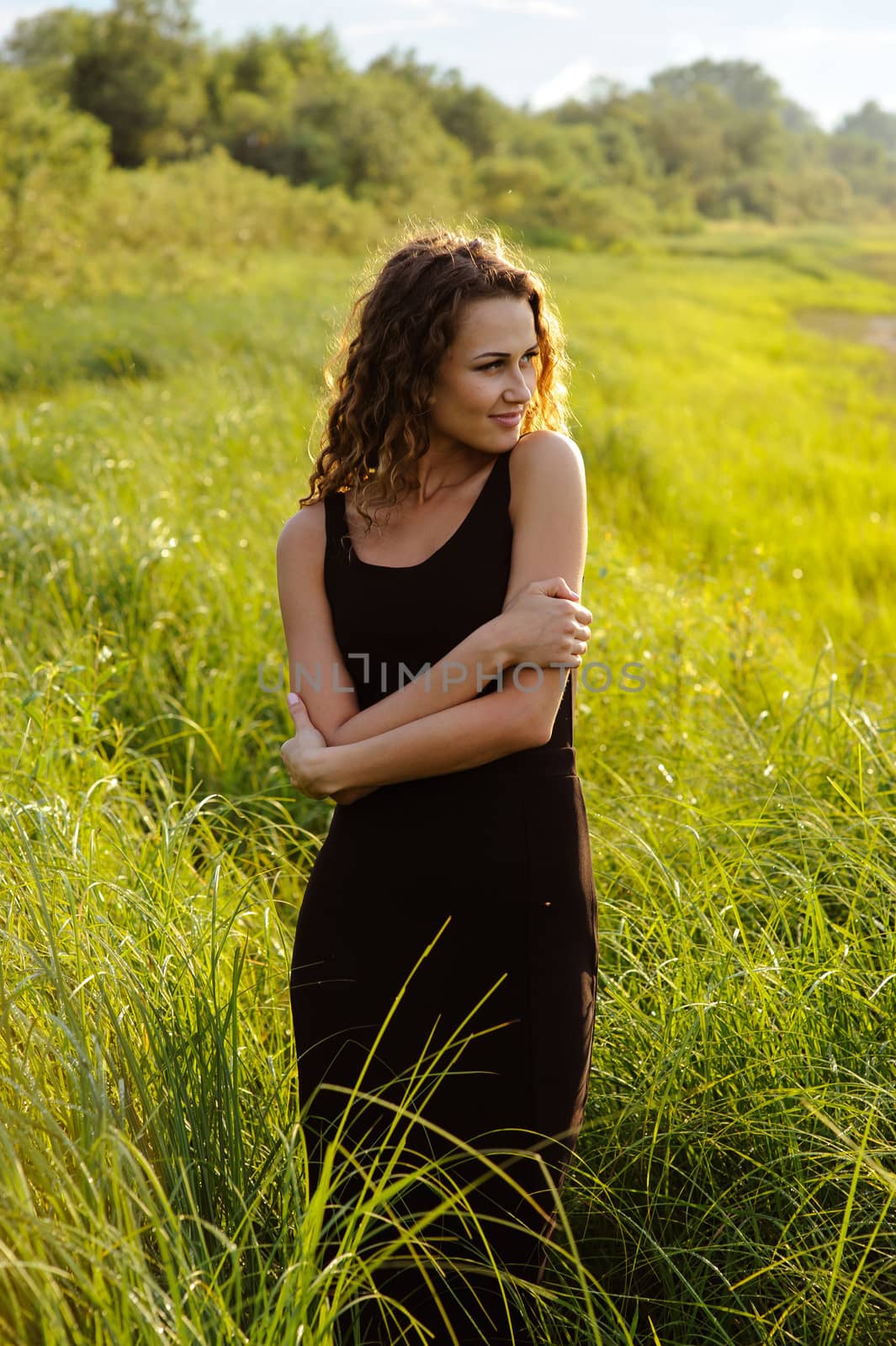 Beautiful girl walks and dreams in high grass on the banks of river