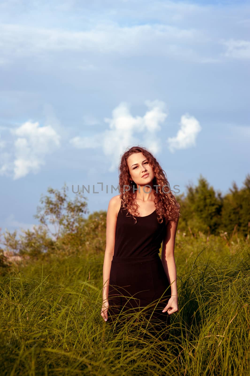 Beautiful girl walks and dreams in high grass on the banks of river