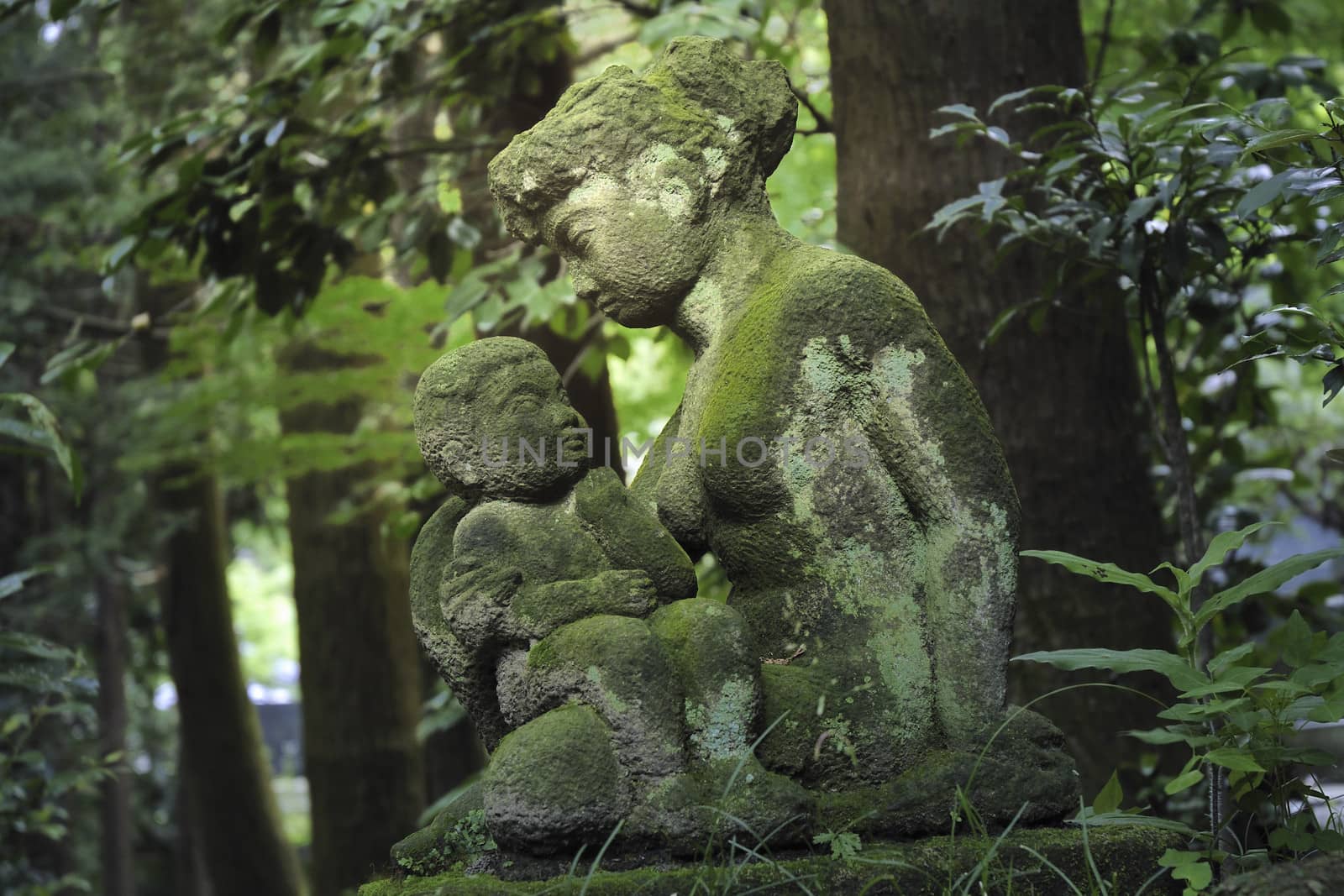 stone sculptures of mother and child inside dark Japanese forest