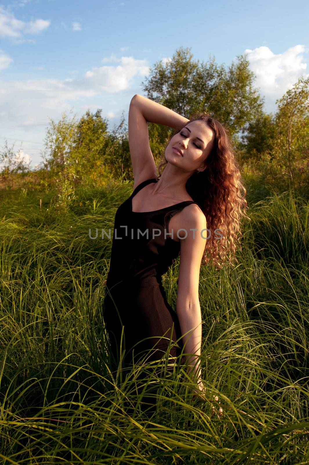 Beautiful girl walks and dreams in high grass on the banks of river