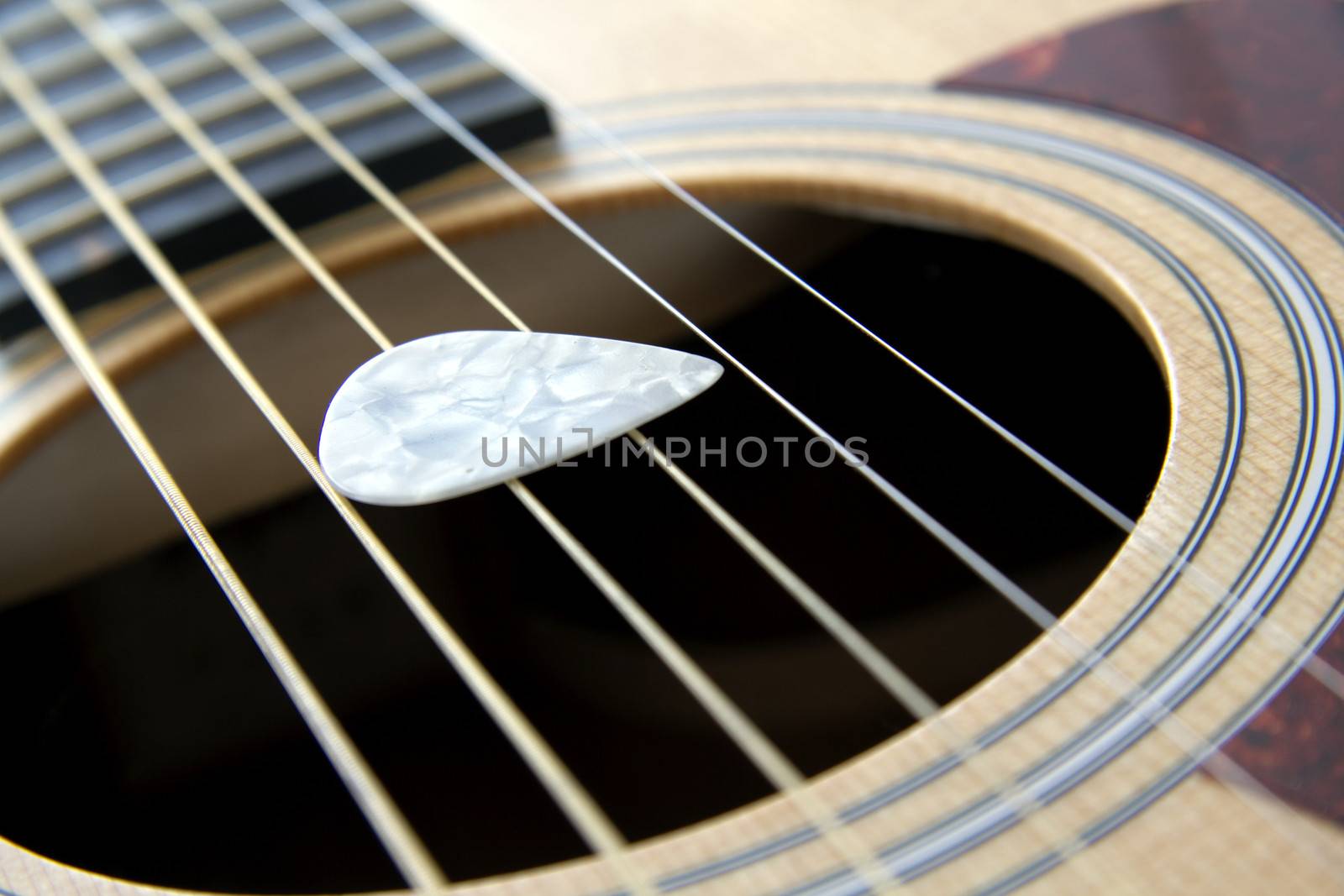White plectrum on a 6 string acoustic guitar