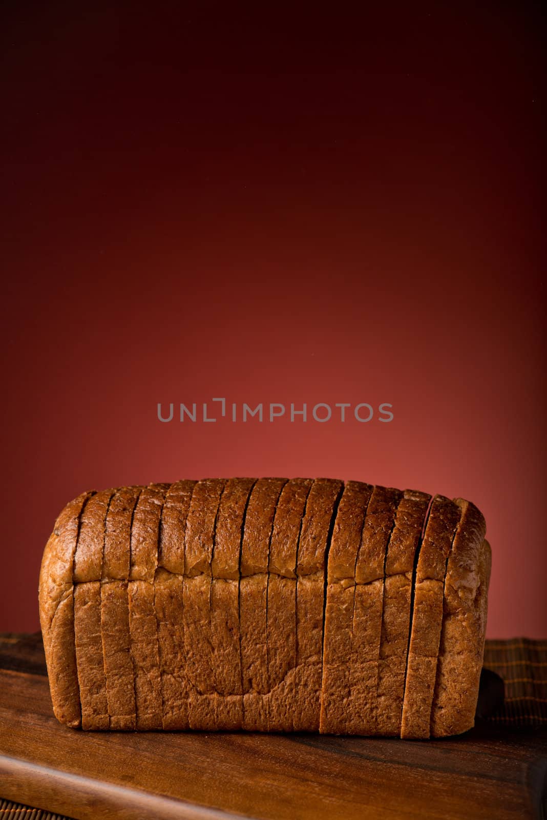 Fresh bread cut in slices on a board isolated on red