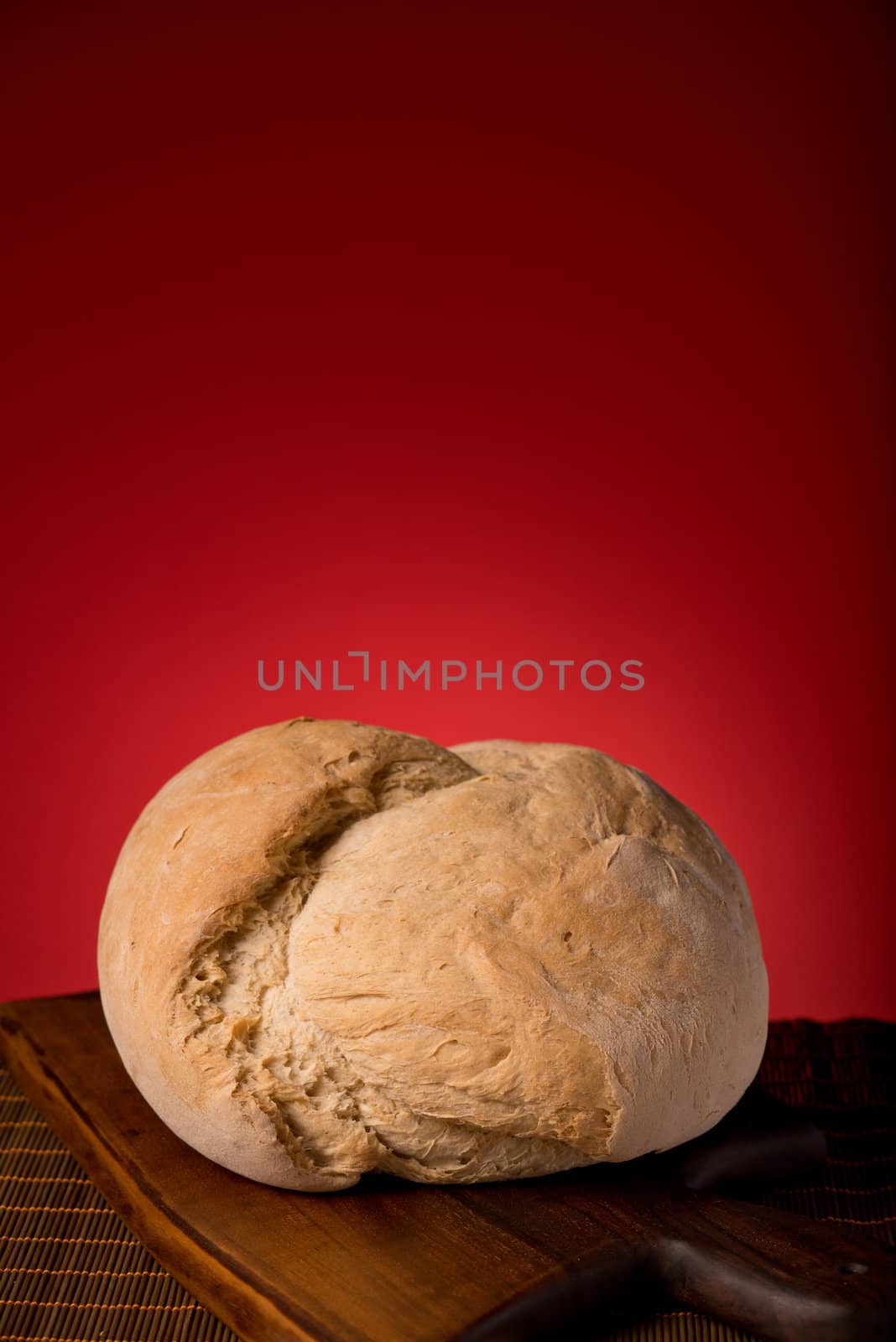 Fresh loaf on a wooden board isolated on red