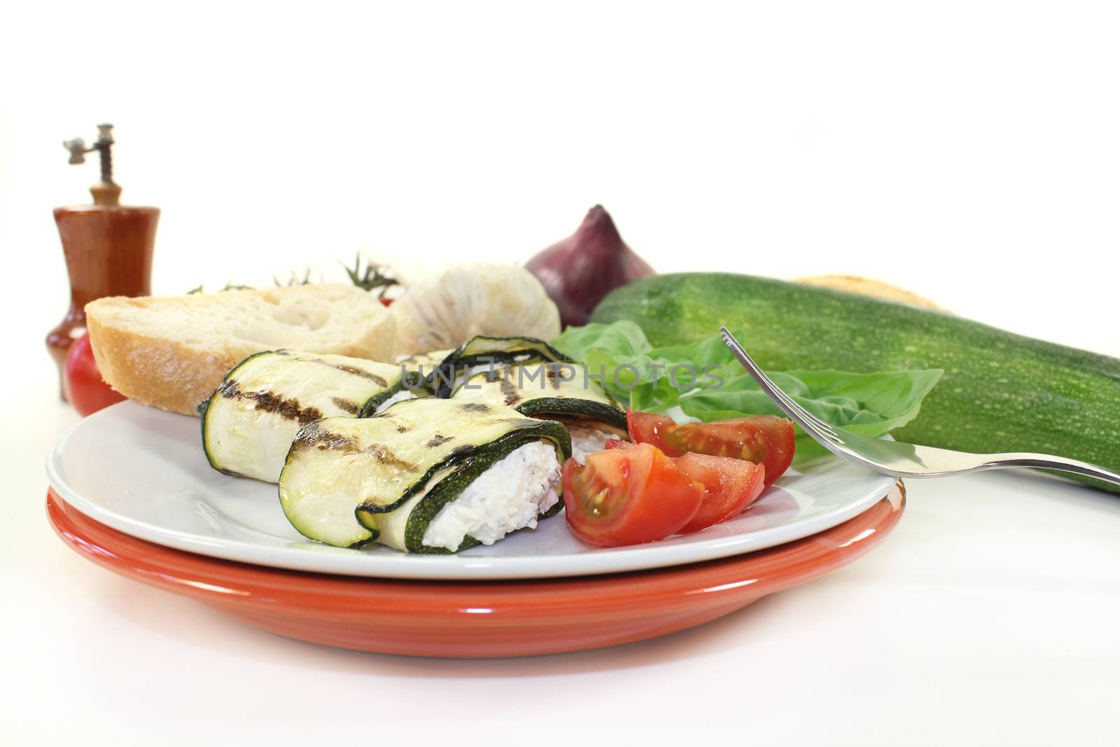 stuffed courgette rolls and tomatoes on a white plate