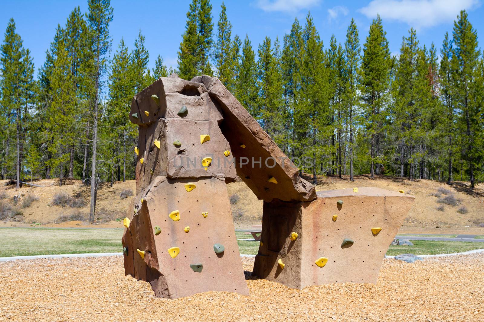 An outdoor rock climbing structure at a playground at a park for kids to practice and play on.