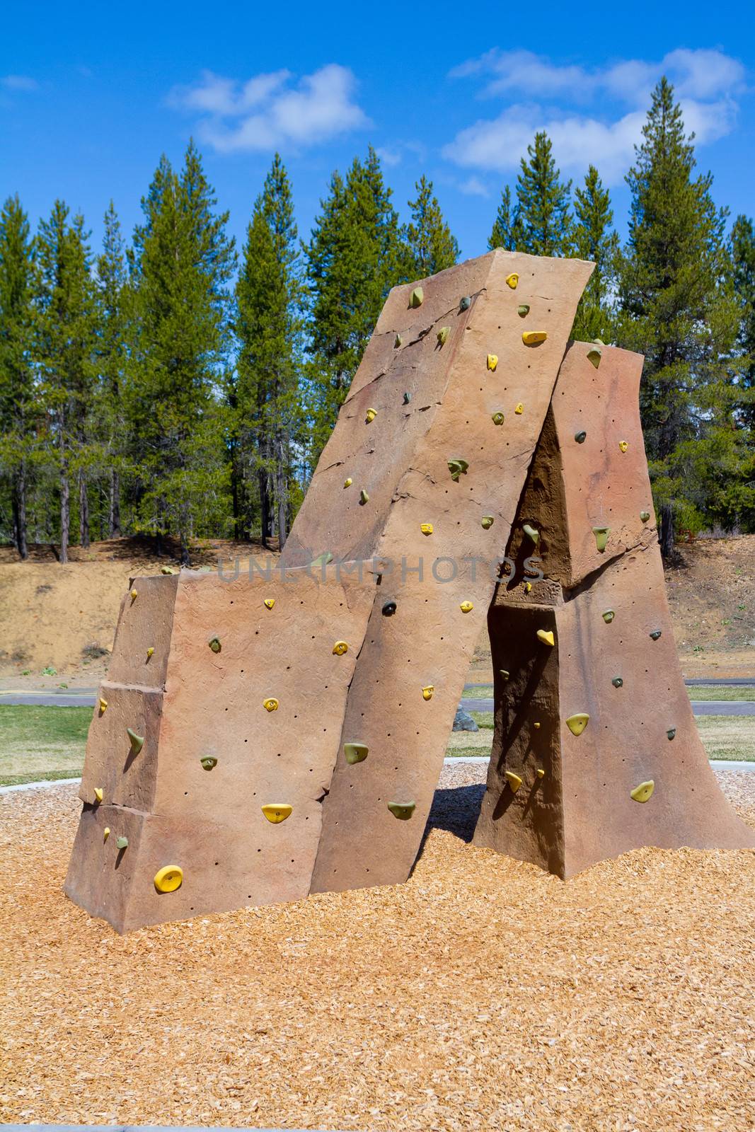 An outdoor rock climbing structure at a playground at a park for kids to practice and play on.