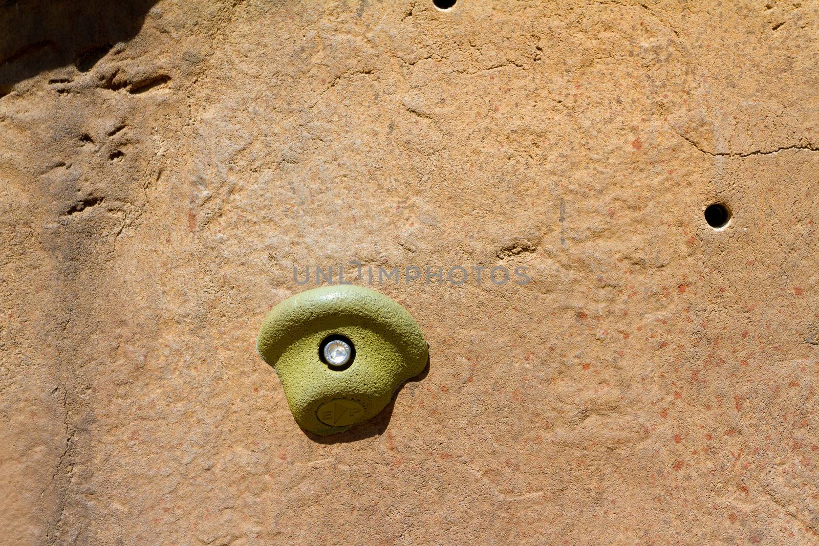 A closeup of a rock climbing wall and the hand holds that are used by climbers to scale the structure.