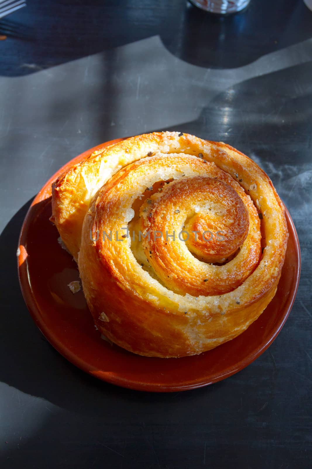 A morning bun cinnamon roll on a plate at a cafe restaurant.