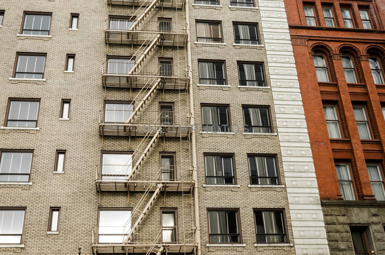 Two different color brick buildings, one with a fire escape running down the side of it in Portland, Oregon