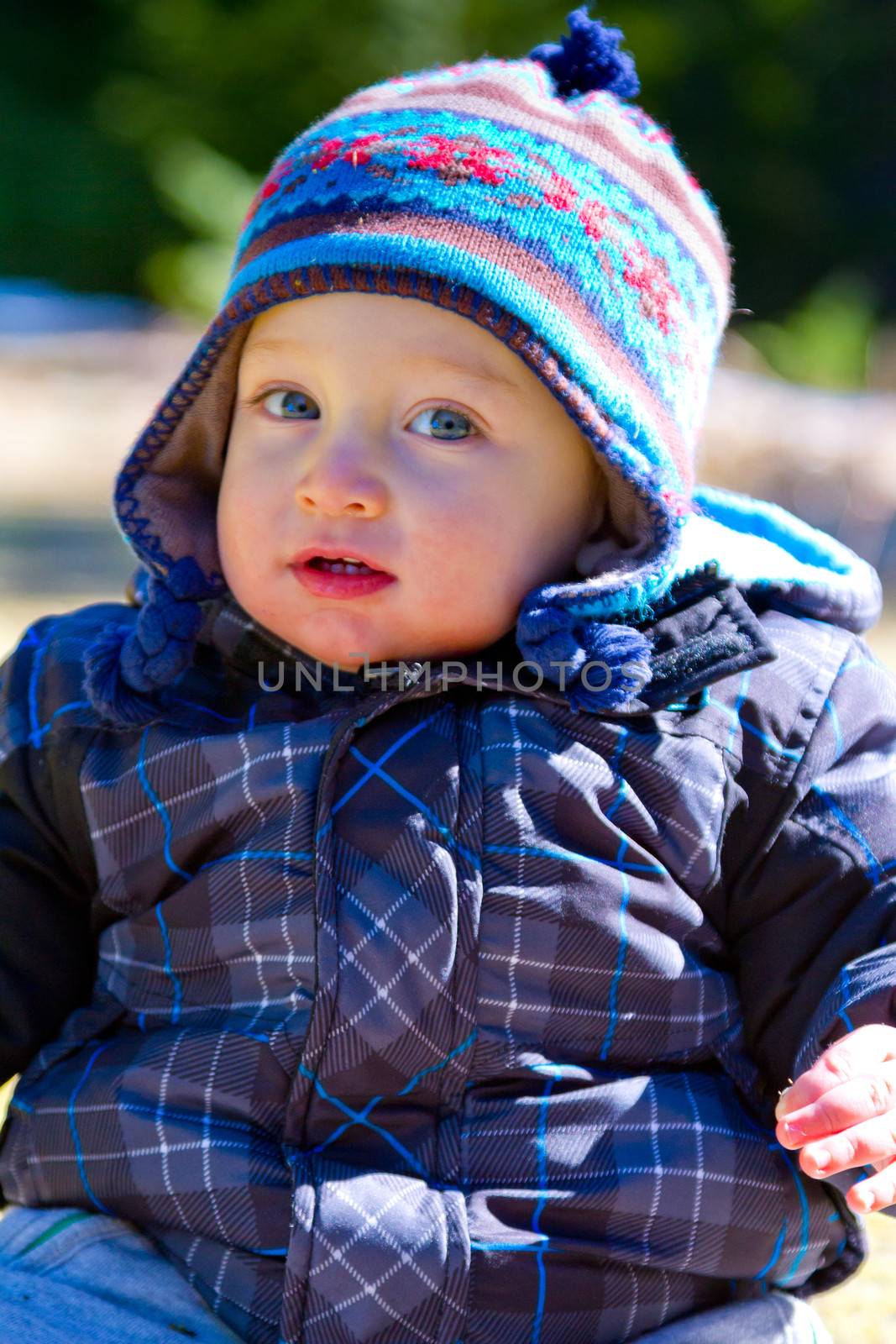 A young boy wears a jacket and warm hat while hiking in the cold near snow in the winter and having fun exploring.