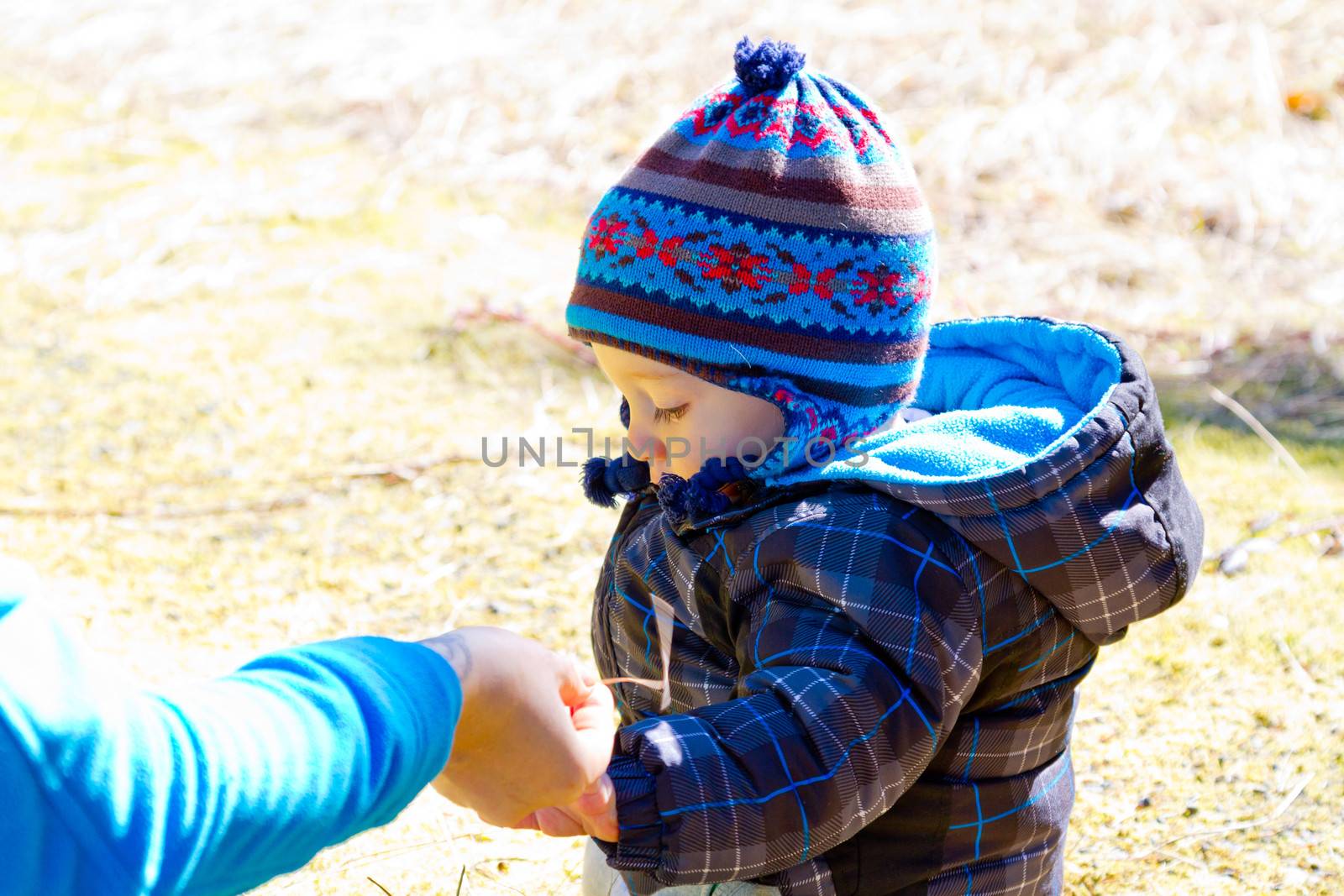 A young boy wears a jacket and warm hat while hiking in the cold near snow in the winter and having fun exploring.