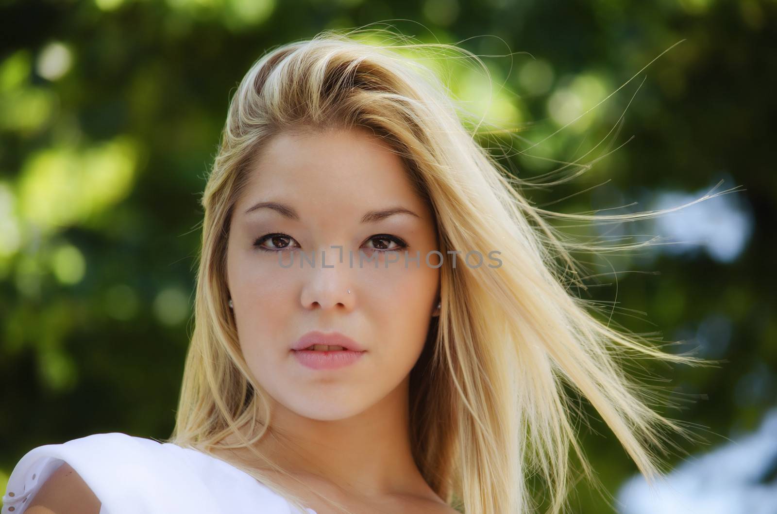 Headshot of pretty blonde girl outdoors in nature looking in camera