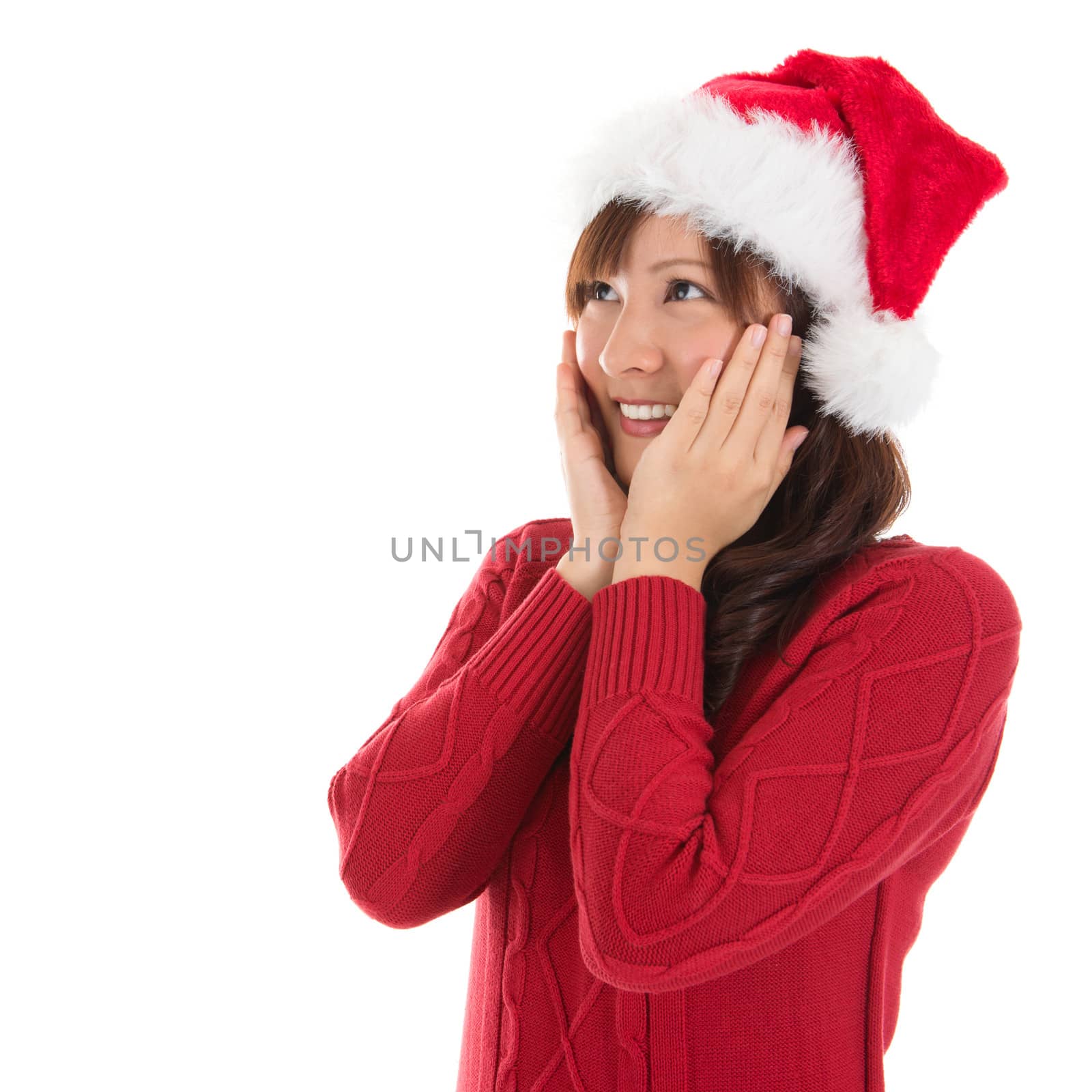 Daydreaming Asian Christmas woman wearing santa hat. Christmas woman portrait of a cute, beautiful smiling Asian Chinese / Japanese model. Isolated on white background.