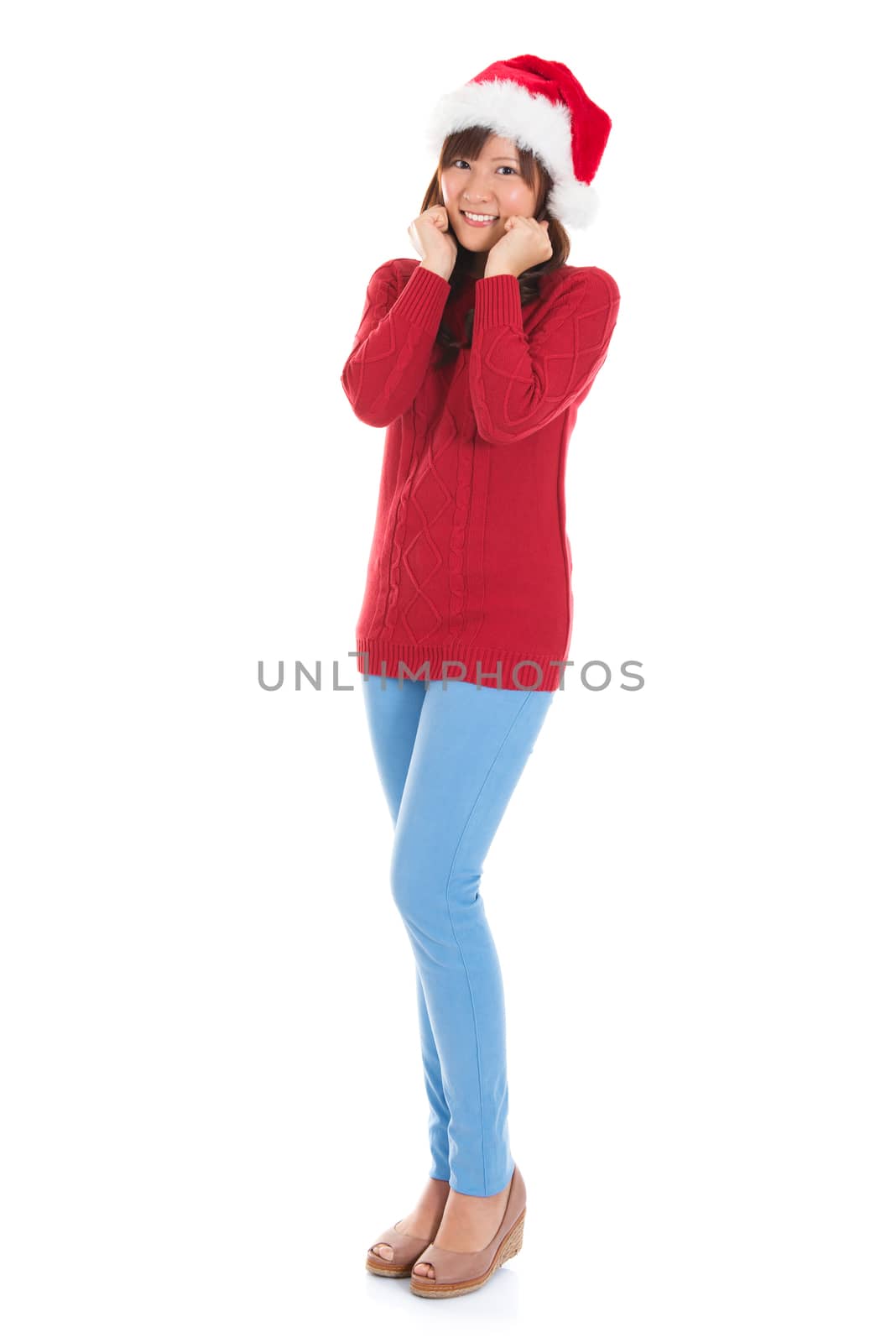 Happy Asian Christmas woman wearing santa hat. Christmas woman portrait of a cute, beautiful smiling Asian Chinese / Japanese model. Full body isolated on white background.
