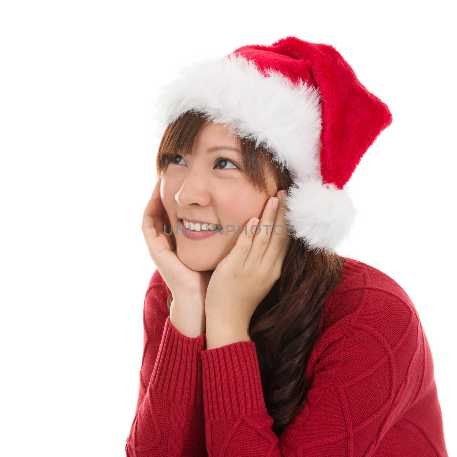 Thoughtful Asian Christmas woman wearing santa hat. Christmas woman portrait of a cute, beautiful smiling Asian Chinese / Japanese model. Isolated on white background.