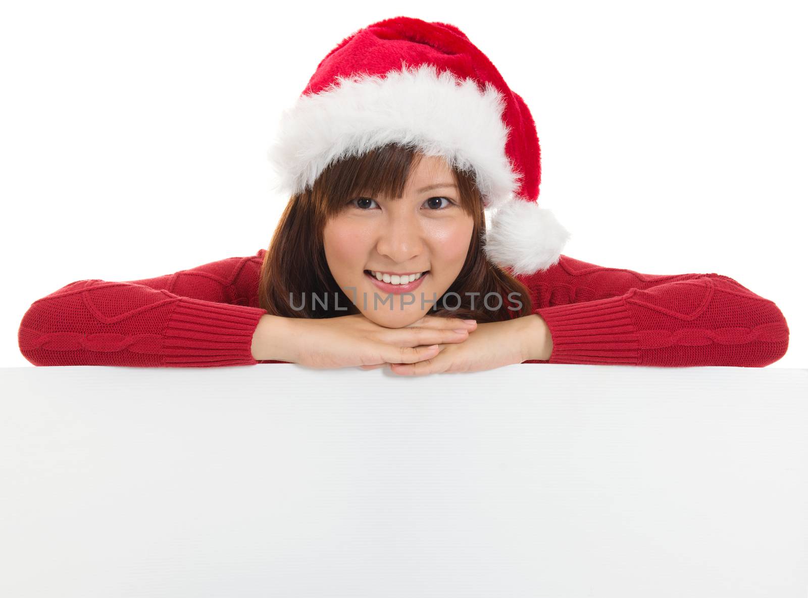 Christmas santa woman smiling cute is showing blank empty billboard sign. Asian Chinese / Japanese  young female model in red Santa hat. Isolated on white background. 