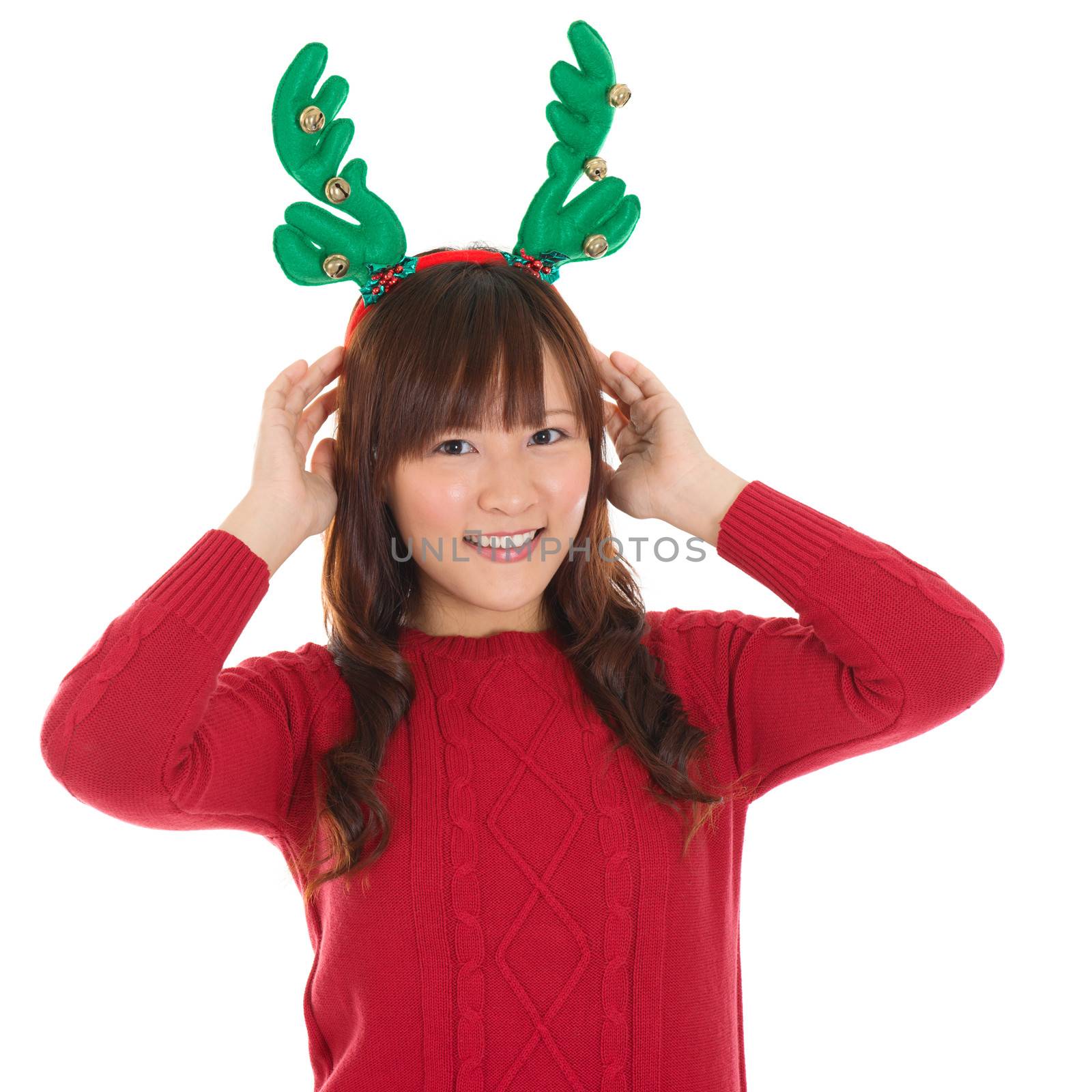 Asian Christmas woman wearing reindeer horns. Christmas woman portrait of a cute, beautiful smiling Asian Chinese / Japanese model. Isolated on white background.