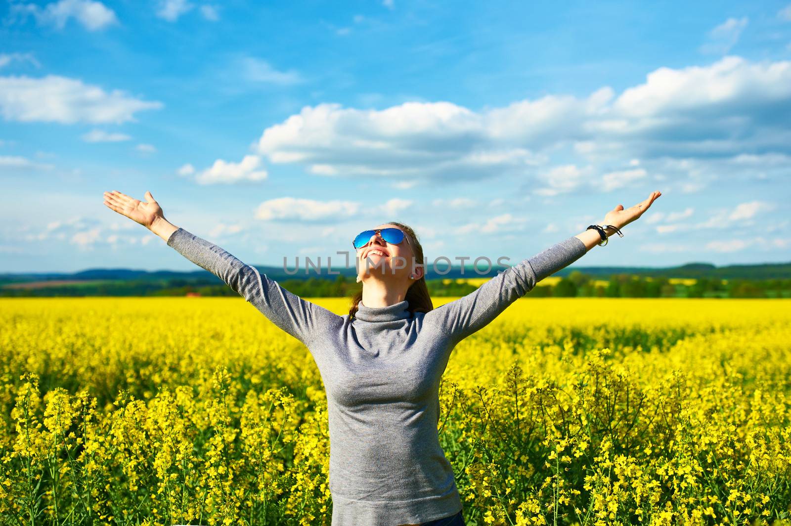 Girl with outstretched arms at colza field