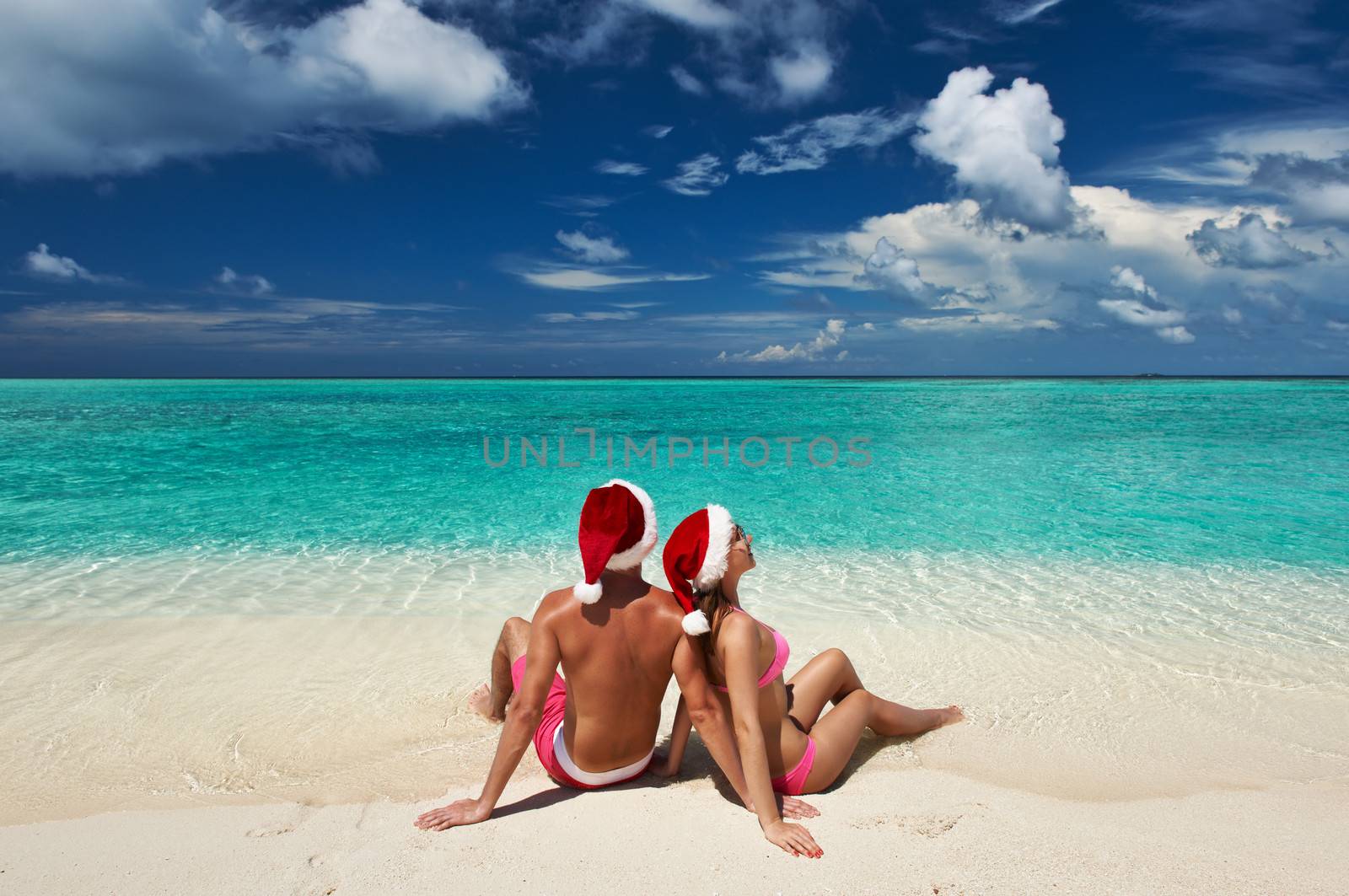 Couple in santa's hat on a tropical beach at Maldives