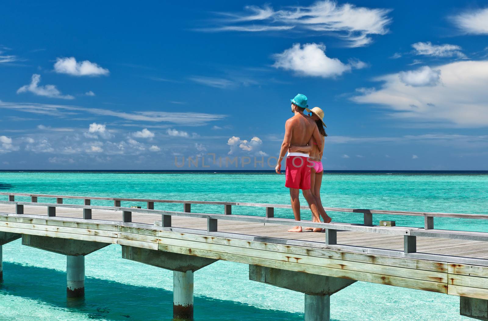 Couple on a tropical beach jetty at Maldives