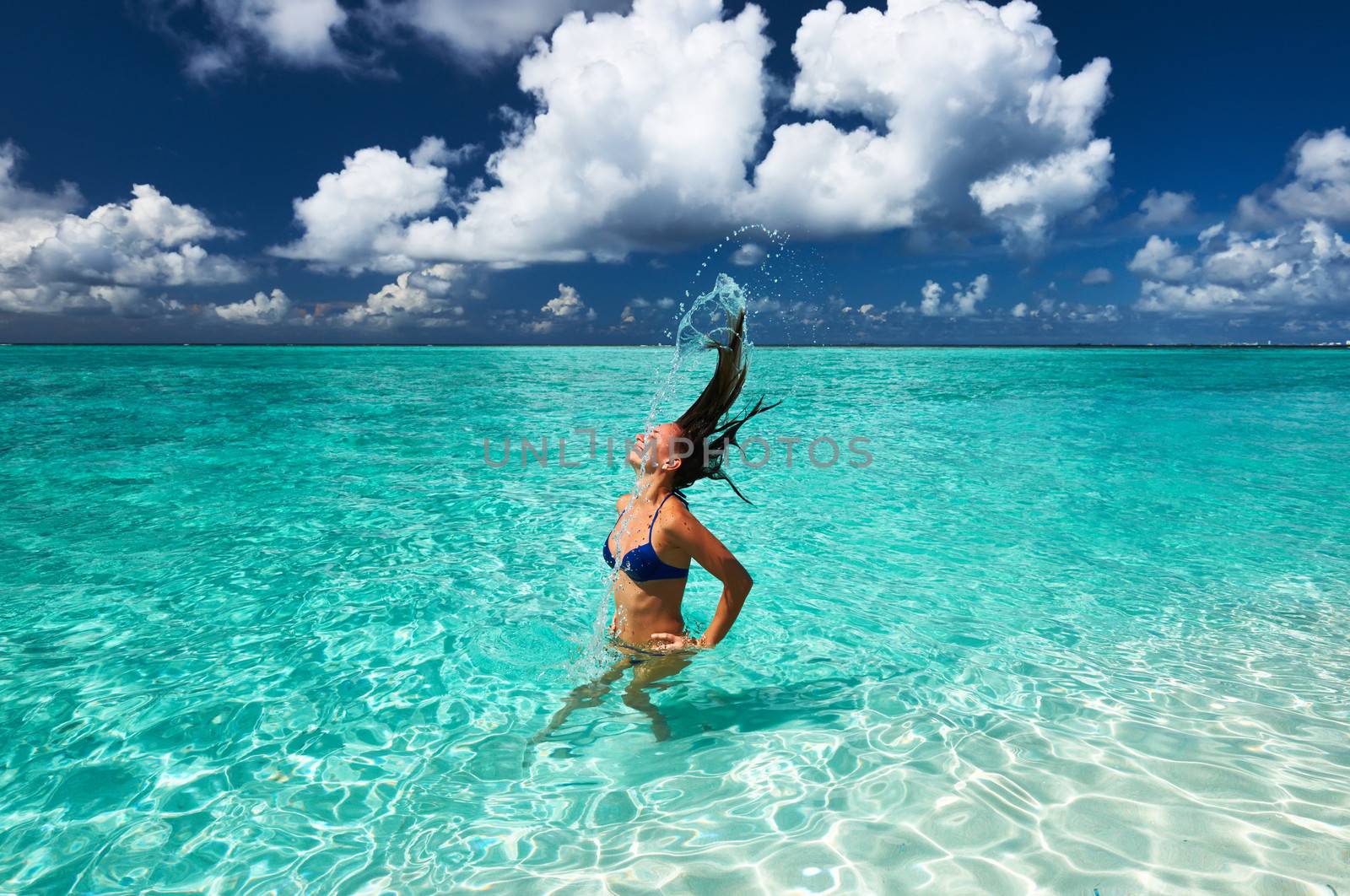 Woman splashing water with hair in the ocean by haveseen