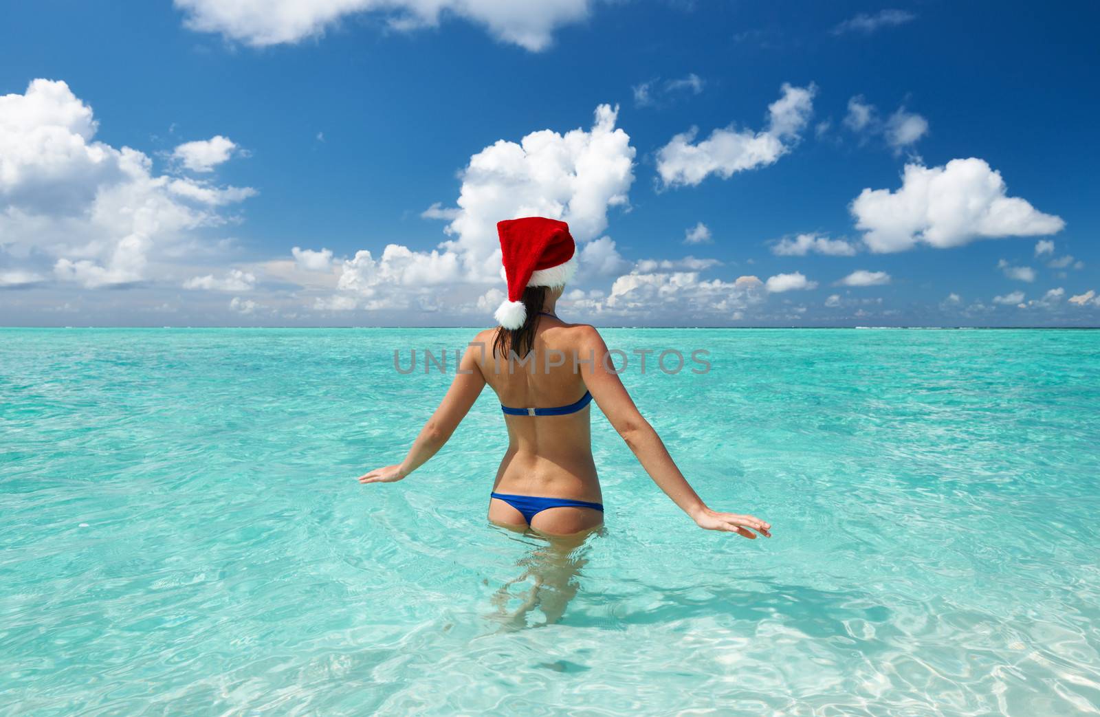 Woman in santa's hat in bikini at tropical beach