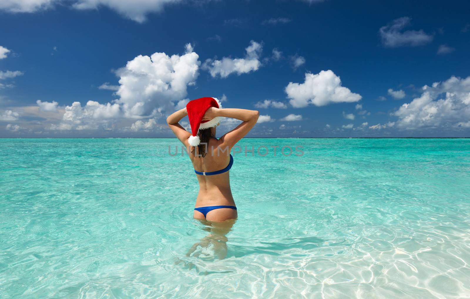 Woman in santa's hat in bikini at tropical beach