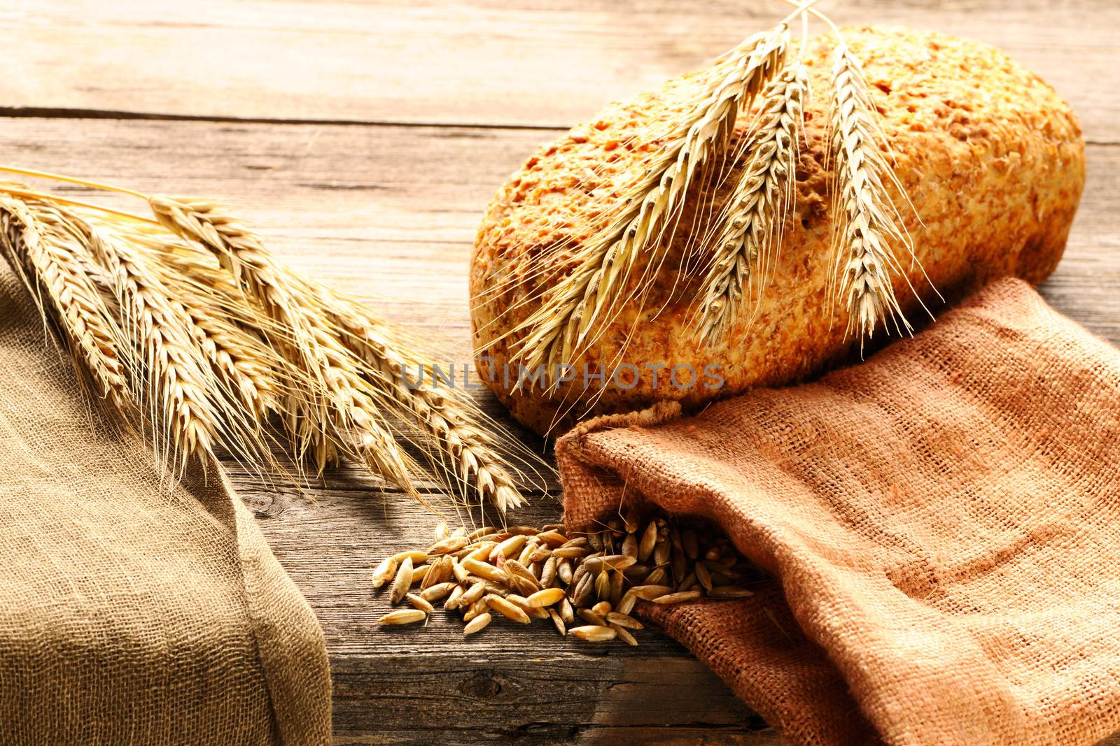 Rye spikelets and bread on wooden background