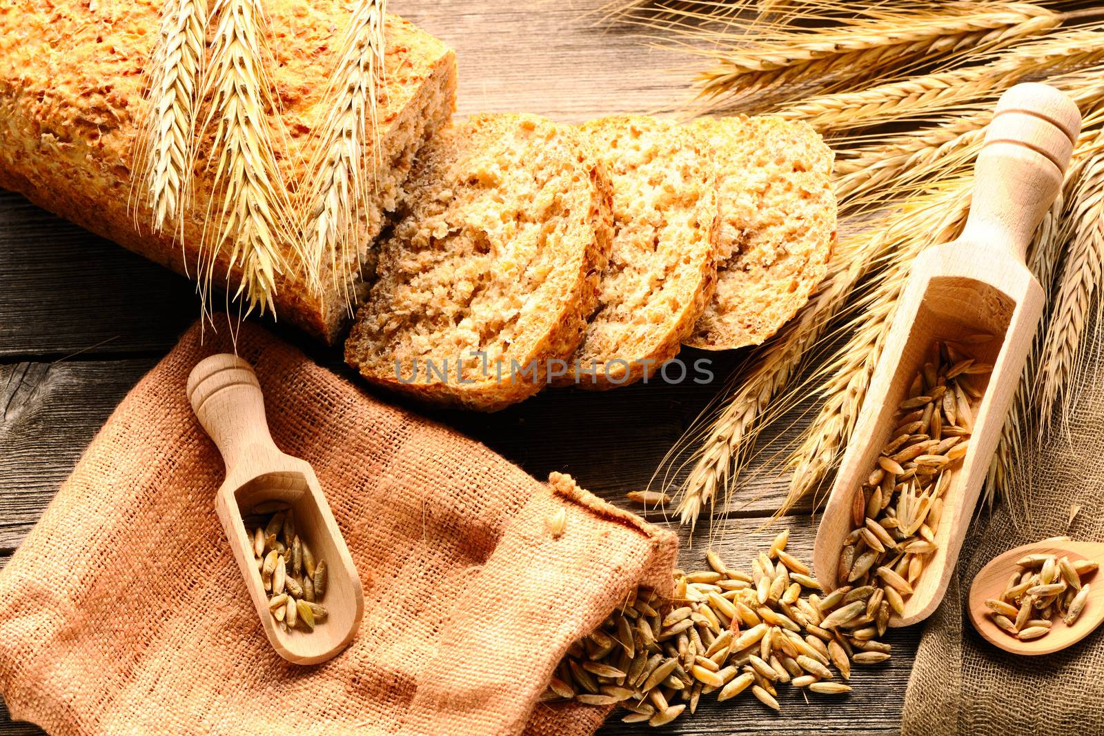 Rye spikelets and sliced bread on wooden background