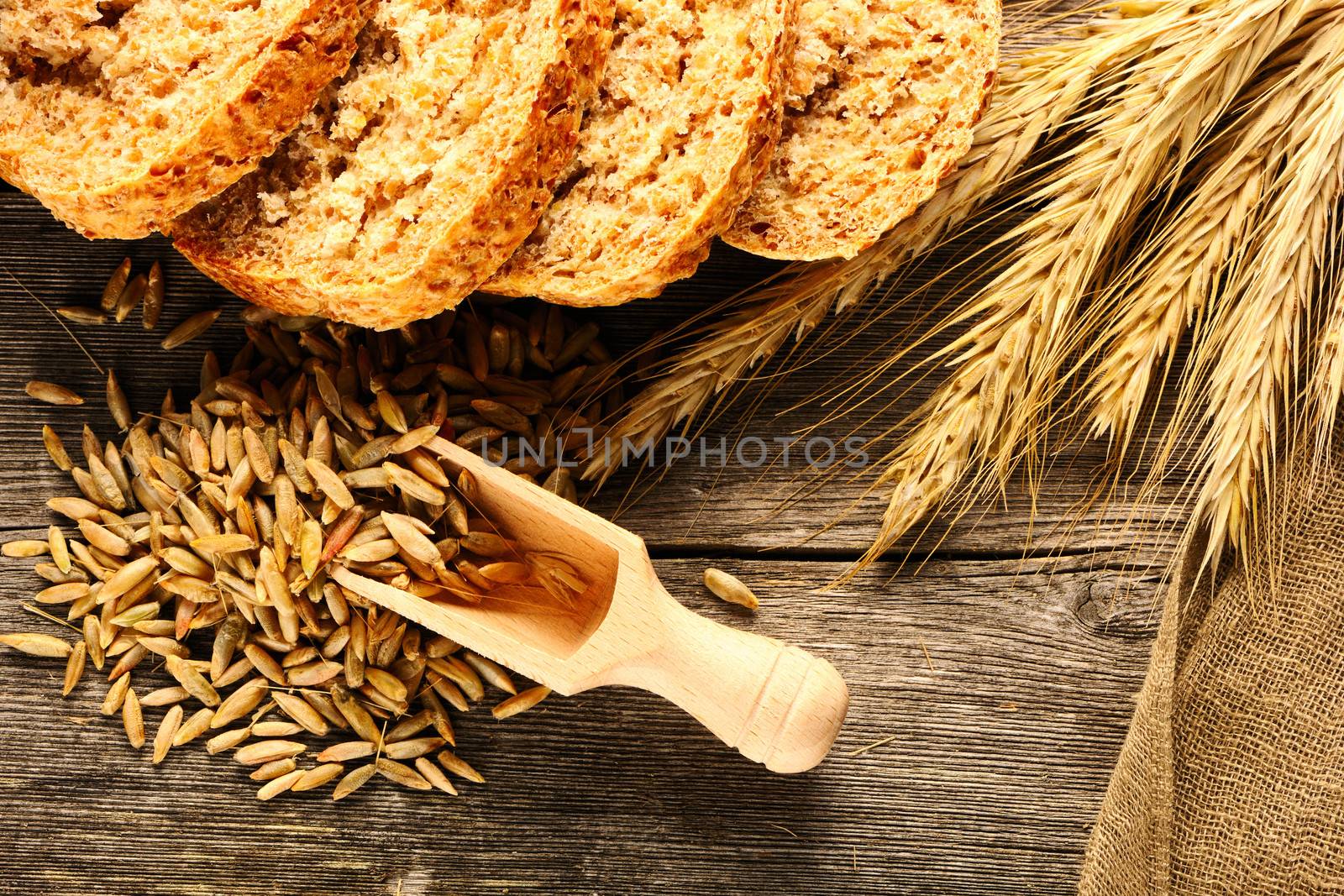 Rye spikelets and sliced bread on wooden background