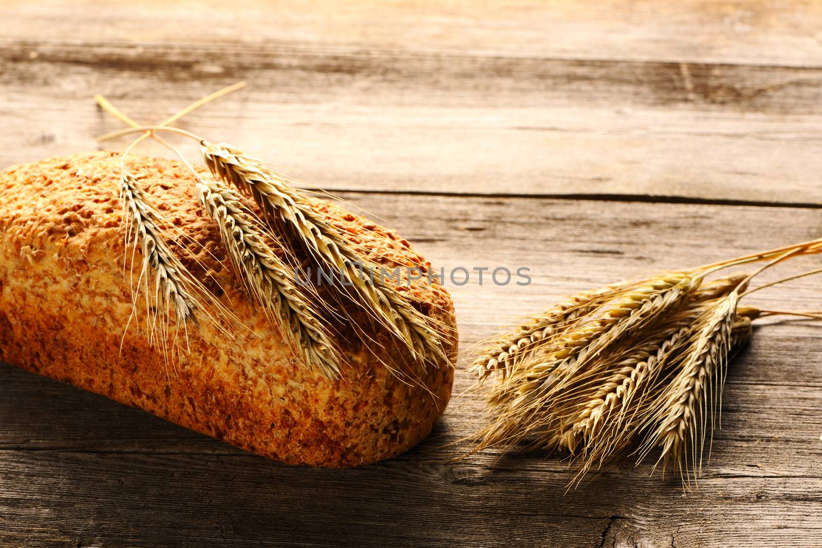 Rye spikelets and bread on wooden background