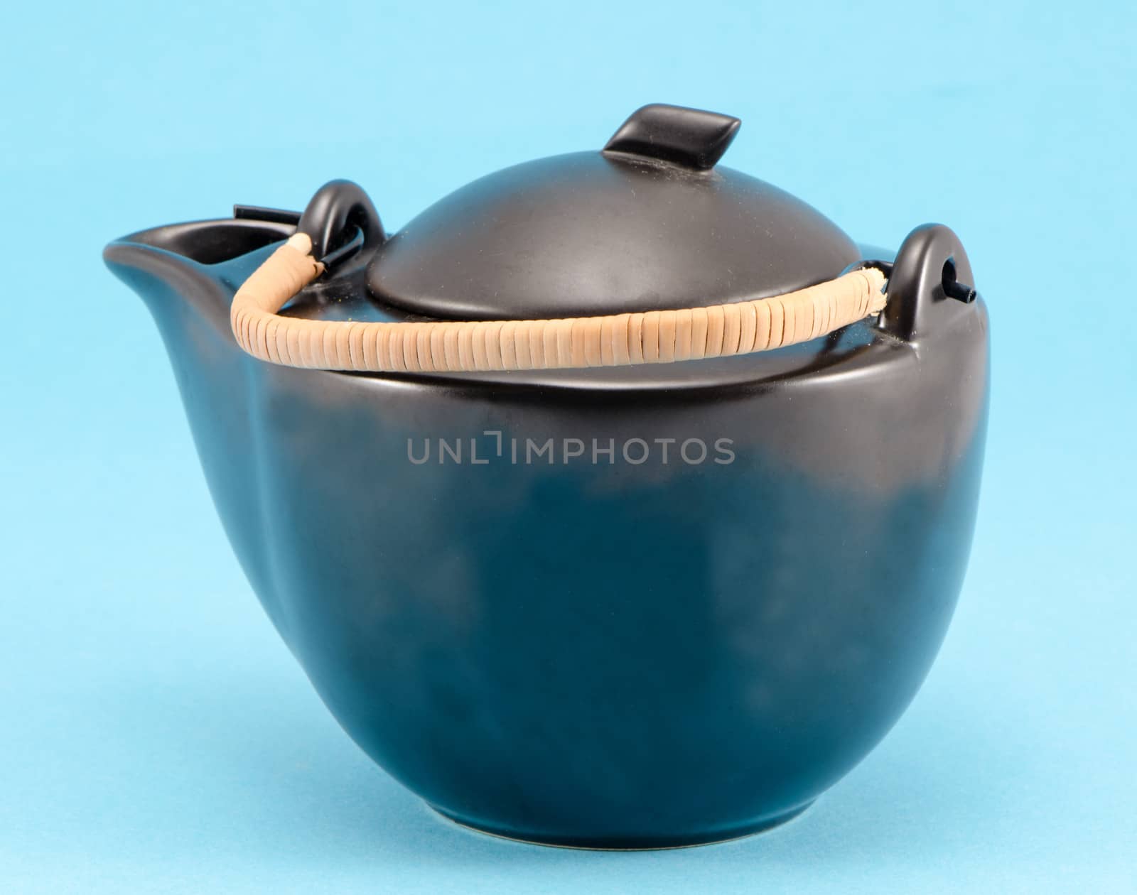 black retro decorative teapot with woven handle on blue background.