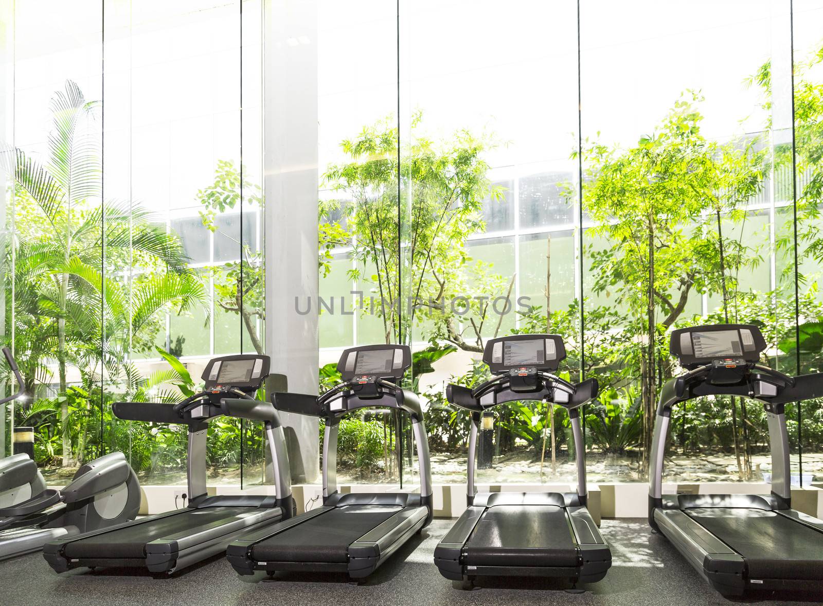 Four Treadmill in a gym with high ceiling in front of a big glass window