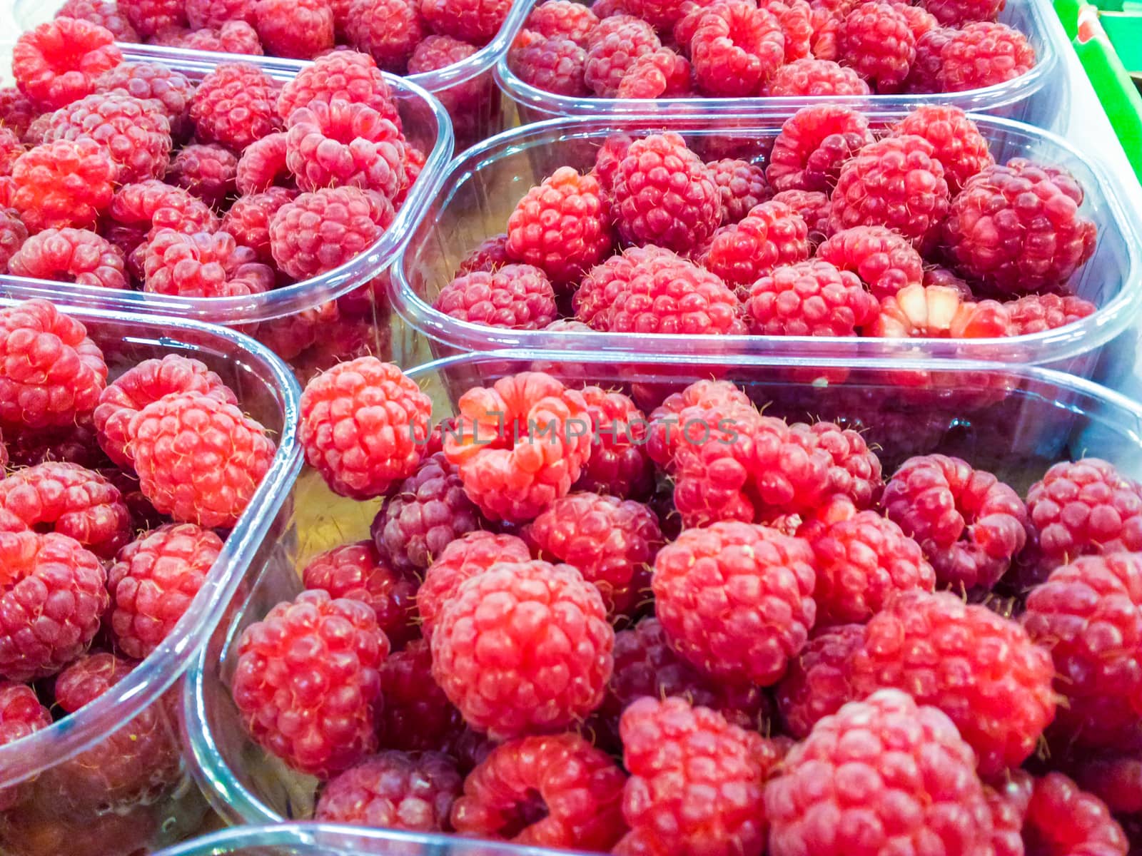 Closeup of raspberries in plastic containers at marketplace